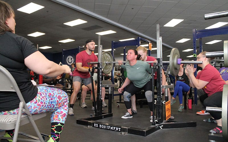 Tucson Strength Barbell Club Powerlifting Classes. Group training class member performs a barbell squat.