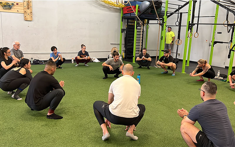 Tucson Strength Bodyweight Training Classes. Group coach demonstrates bodyweight exercise to a group fitness class